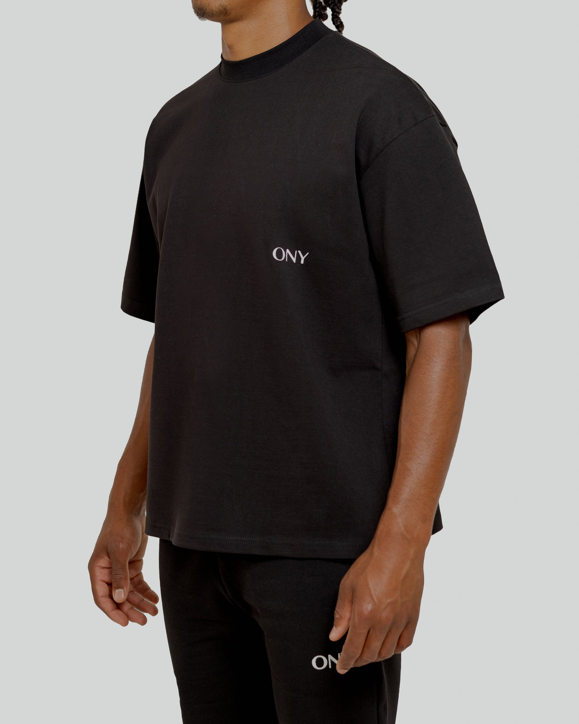 A male model wearing our black oversized tee with a slightly cropped body length and a boxy fit.