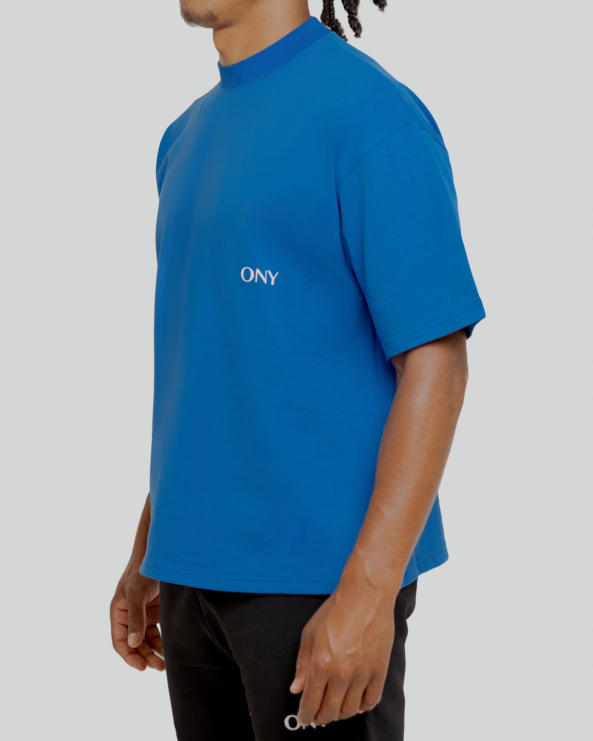 A male model wearing our blue oversized tee with a slightly cropped body length and a boxy fit.