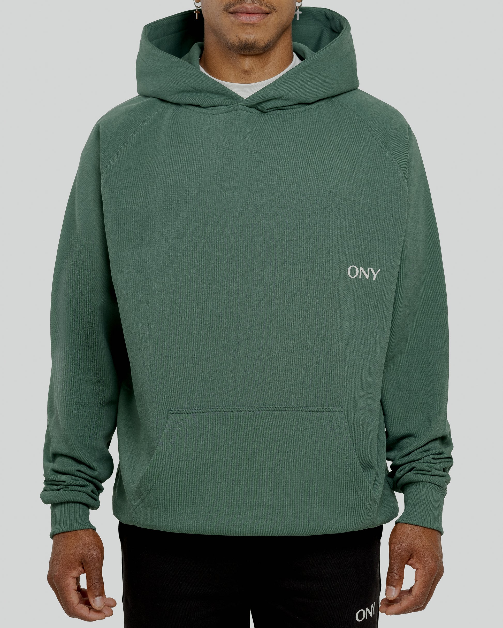 A male model wearing a stylish green oversized hoodie, perfect for a comfortable and fashionable look.  