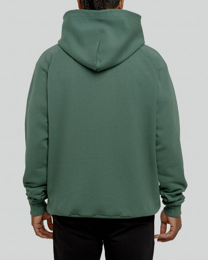 A male model wearing a stylish green oversized hoodie, perfect for a comfortable and fashionable look.  