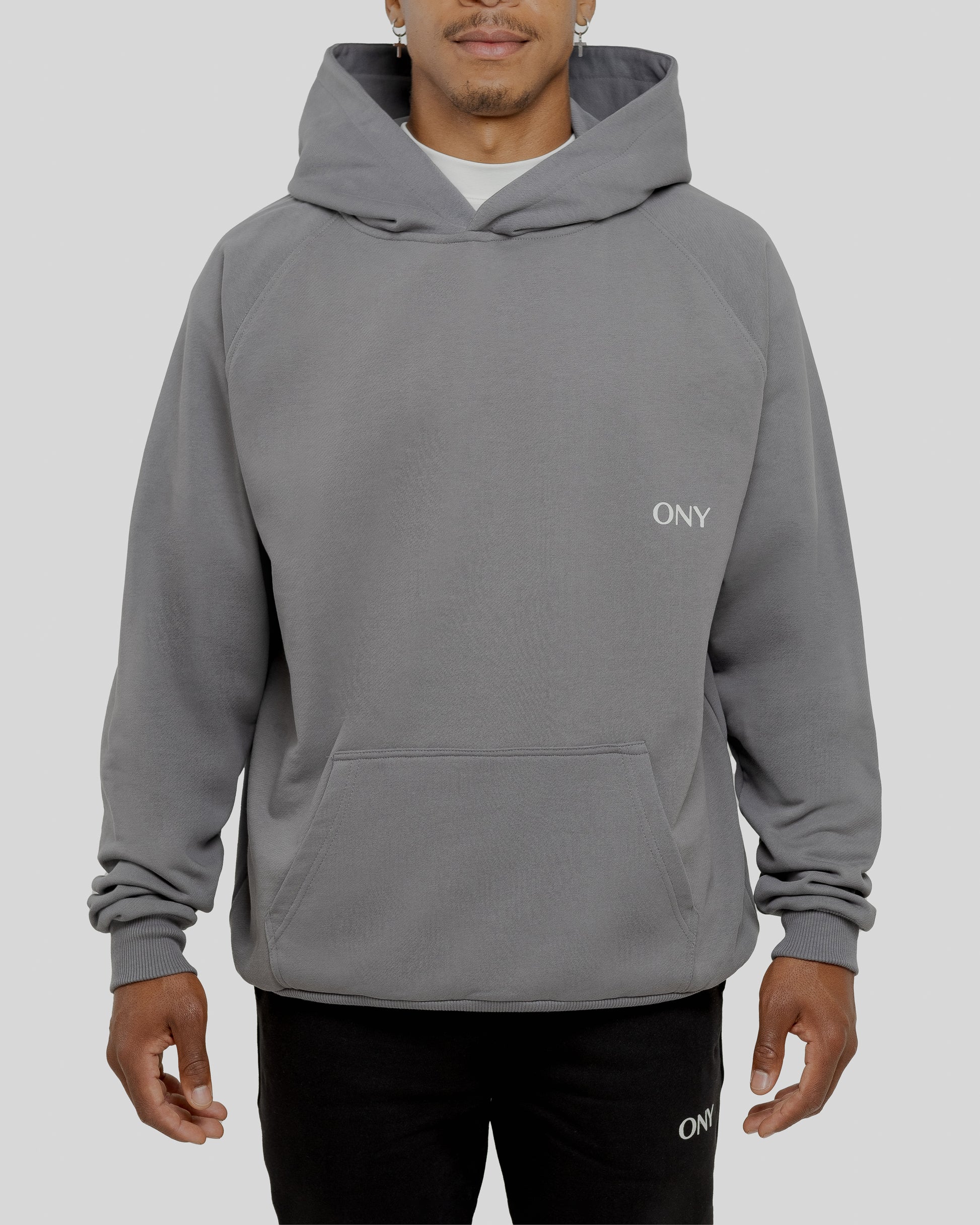 A male model wearing a stylish grey oversized hoodie, perfect for a comfortable and fashionable look.  