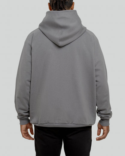 A male model wearing a stylish grey oversized hoodie, perfect for a comfortable and fashionable look.  