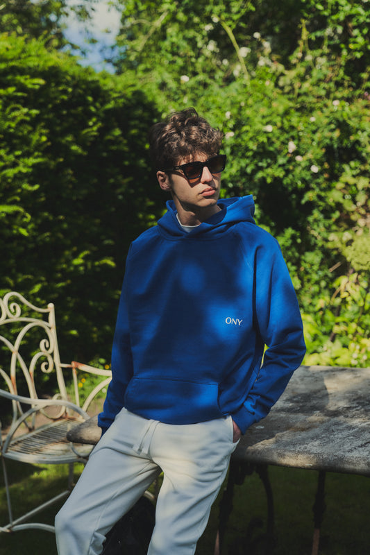 A male model wearing a stylish blue oversized hoodie, perfect for a comfortable and fashionable look, styled with our off-white sweatpants for a laid-back yet fashionable look 