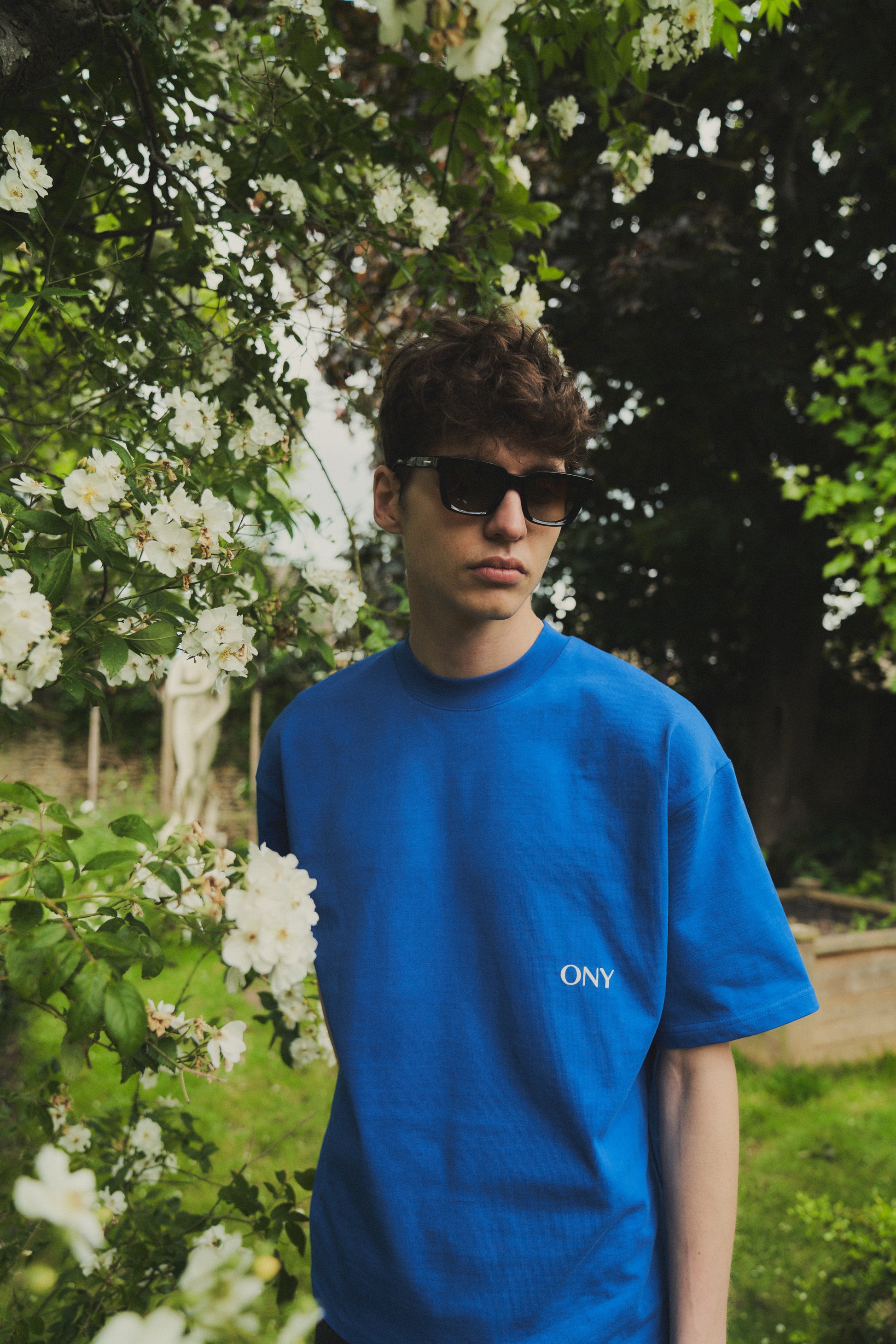 A male model wearing our blue oversized tee with a slightly cropped body length and a boxy fit, perfect for a modern and relaxed look. 