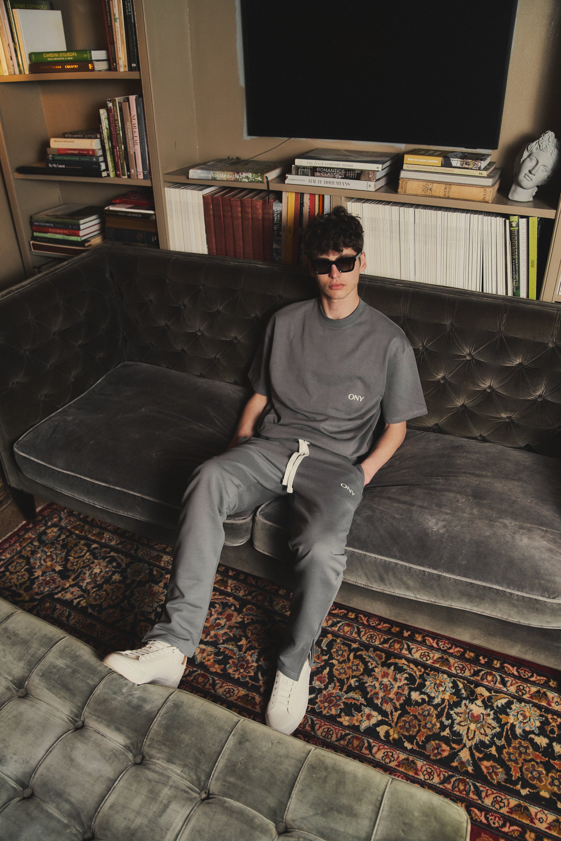 A male model wearing our grey oversized tee with a slightly cropped body length and a boxy fit, styled with our grey split sweatpants for a laid-back yet fashionable look.