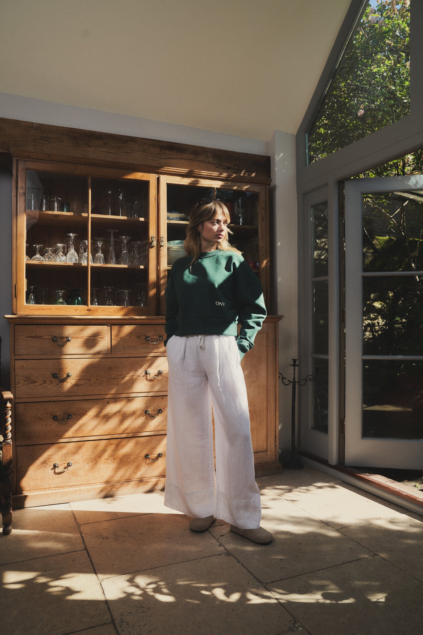 A female model wearing our green women's cropped sweatshirt, featuring a slightly oversized fit and a trendy cropped style above the waist, perfect for a fashion-forward and casual ensemble.