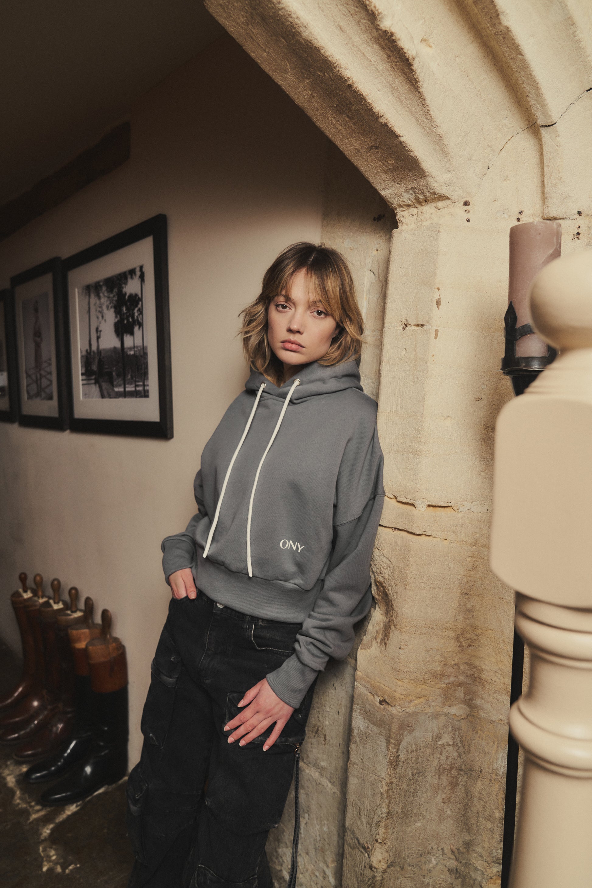 A female model showcasing our grey cropped hoodie, styled with a slightly oversized fit and a modern cropped silhouette waist, perfect for a trendy and relaxed look. 