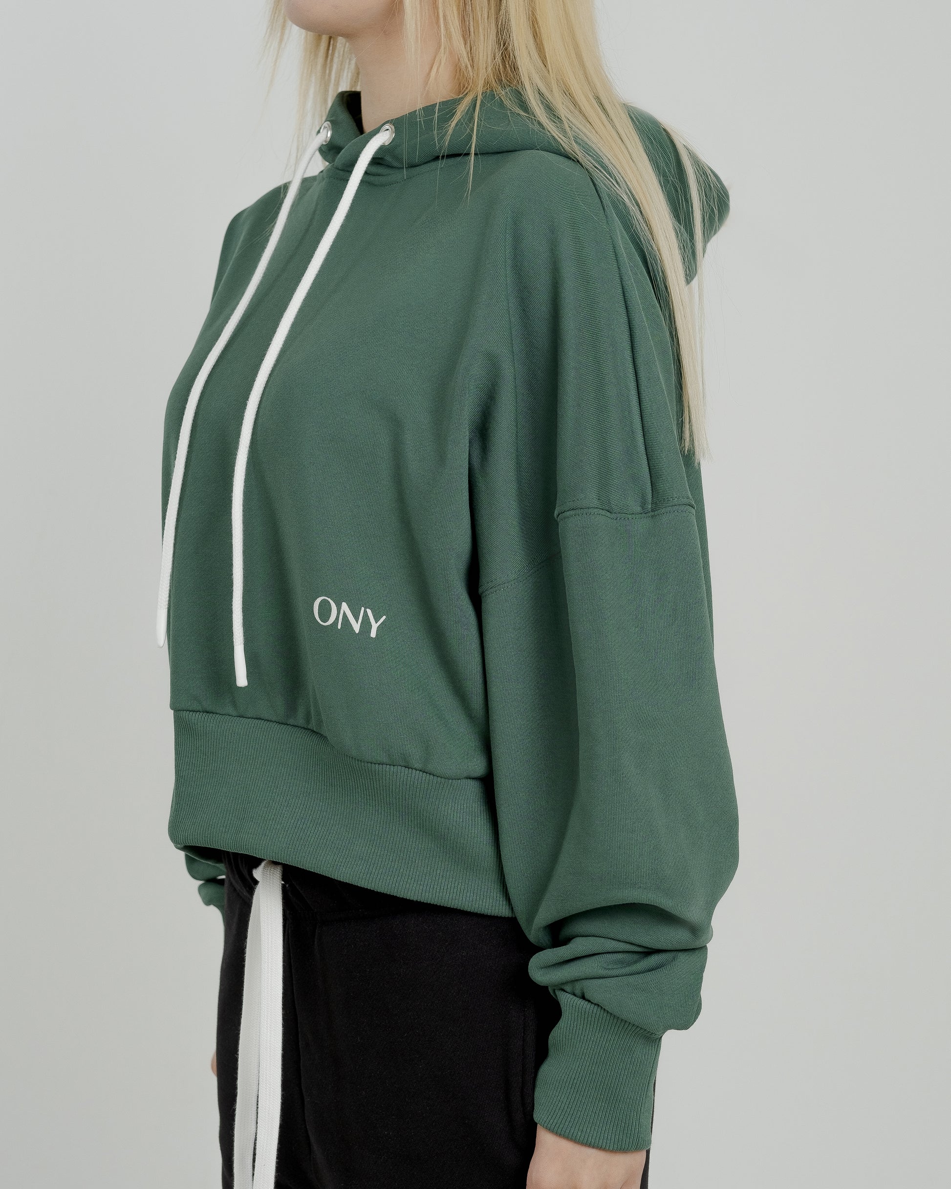 A female model showcasing our green cropped hoodie, styled with a slightly oversized fit and a modern cropped silhouette waist, perfect for a trendy and relaxed look. 