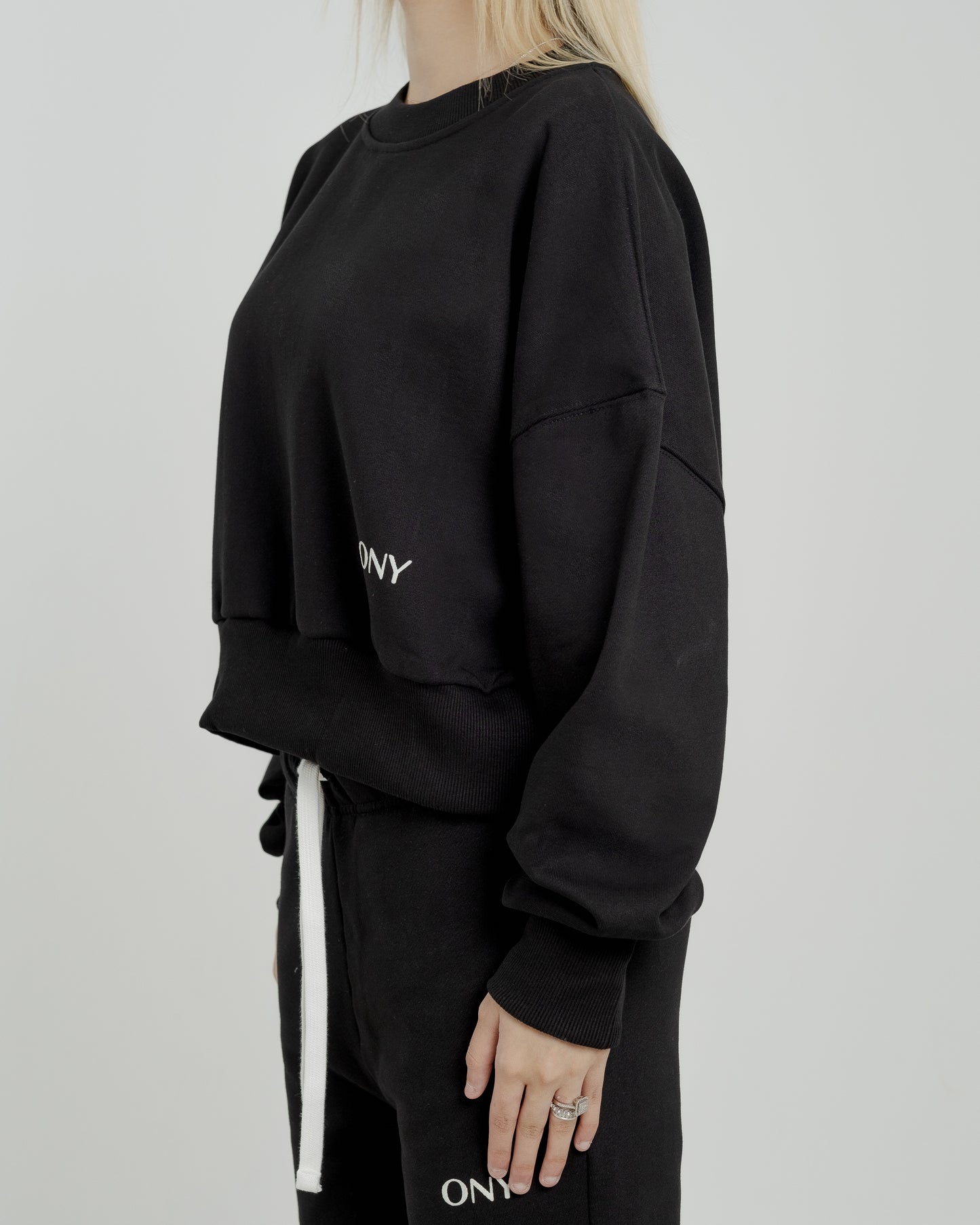 A female model wearing our black women's cropped sweatshirt, exuding a casual and stylish vibe for a modern wardrobe.