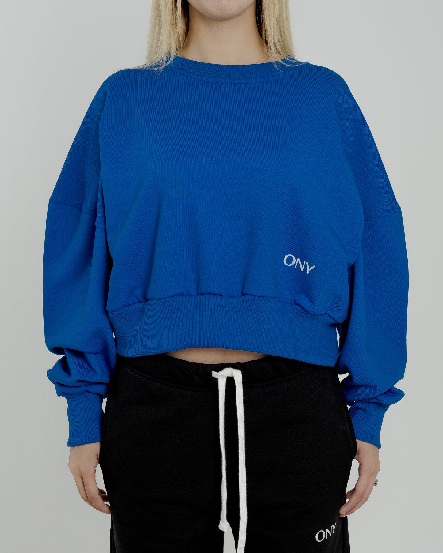 A female model wearing our blue women's cropped sweatshirt, exuding a casual and stylish vibe for a modern wardrobe.