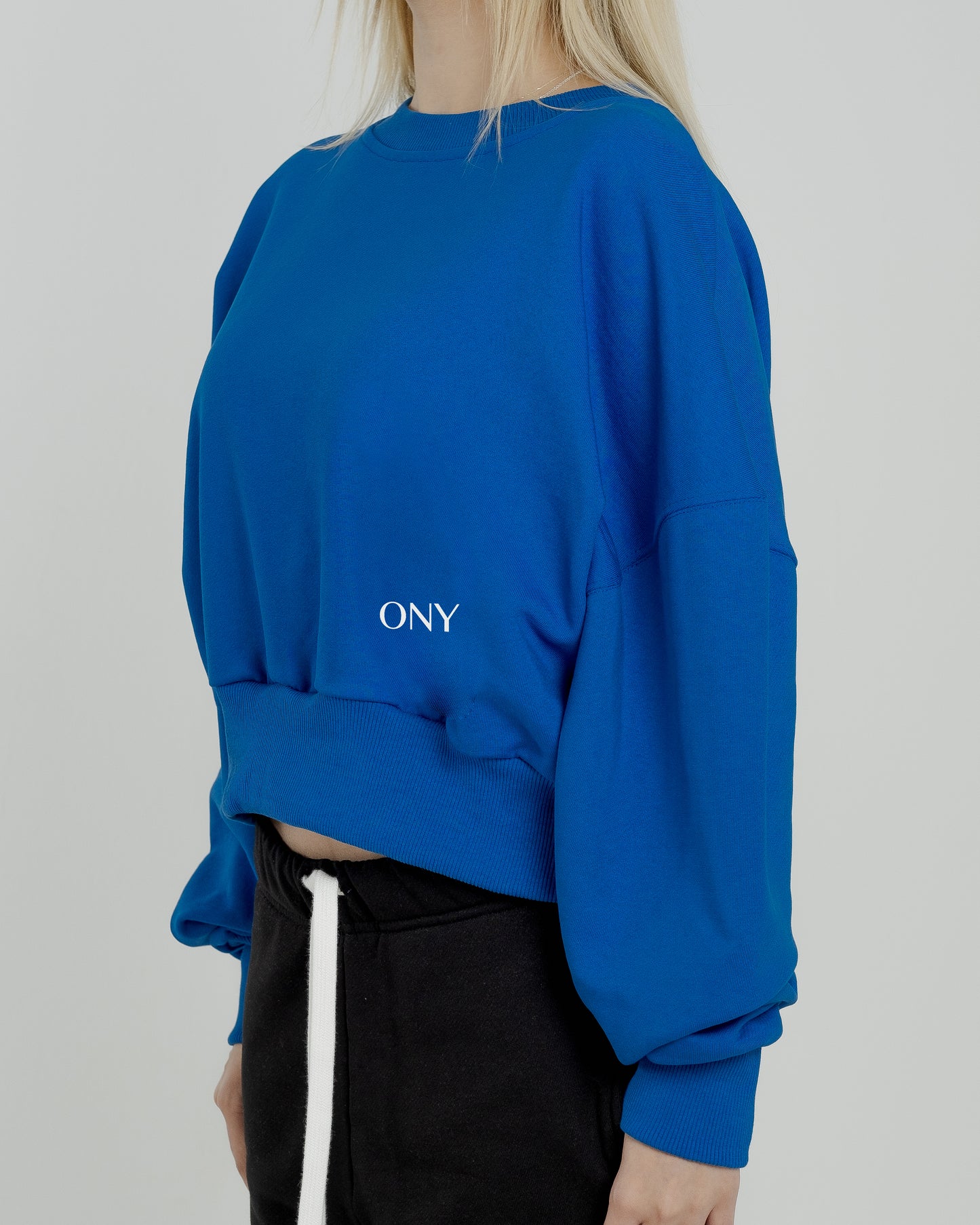 A female model wearing our blue women's cropped sweatshirt, exuding a casual and stylish vibe for a modern wardrobe.