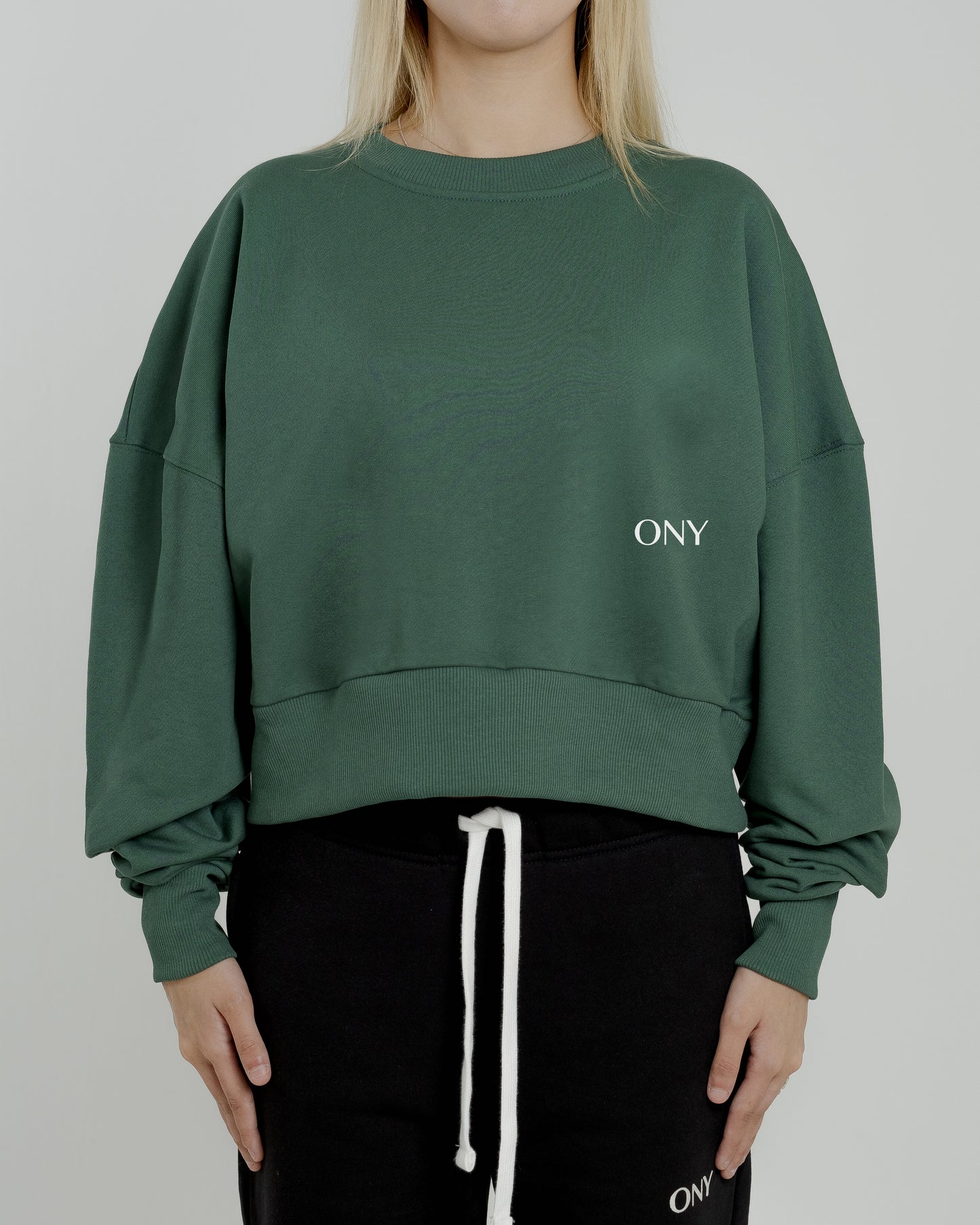 A female model wearing our green women's cropped sweatshirt, exuding a casual and stylish vibe for a modern wardrobe.