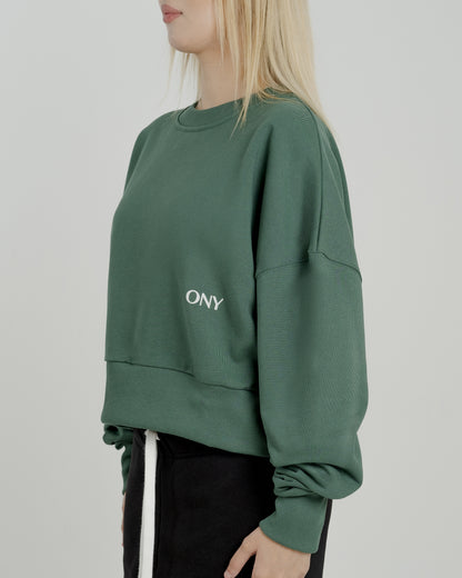 A female model wearing our green women's cropped sweatshirt, exuding a casual and stylish vibe for a modern wardrobe.