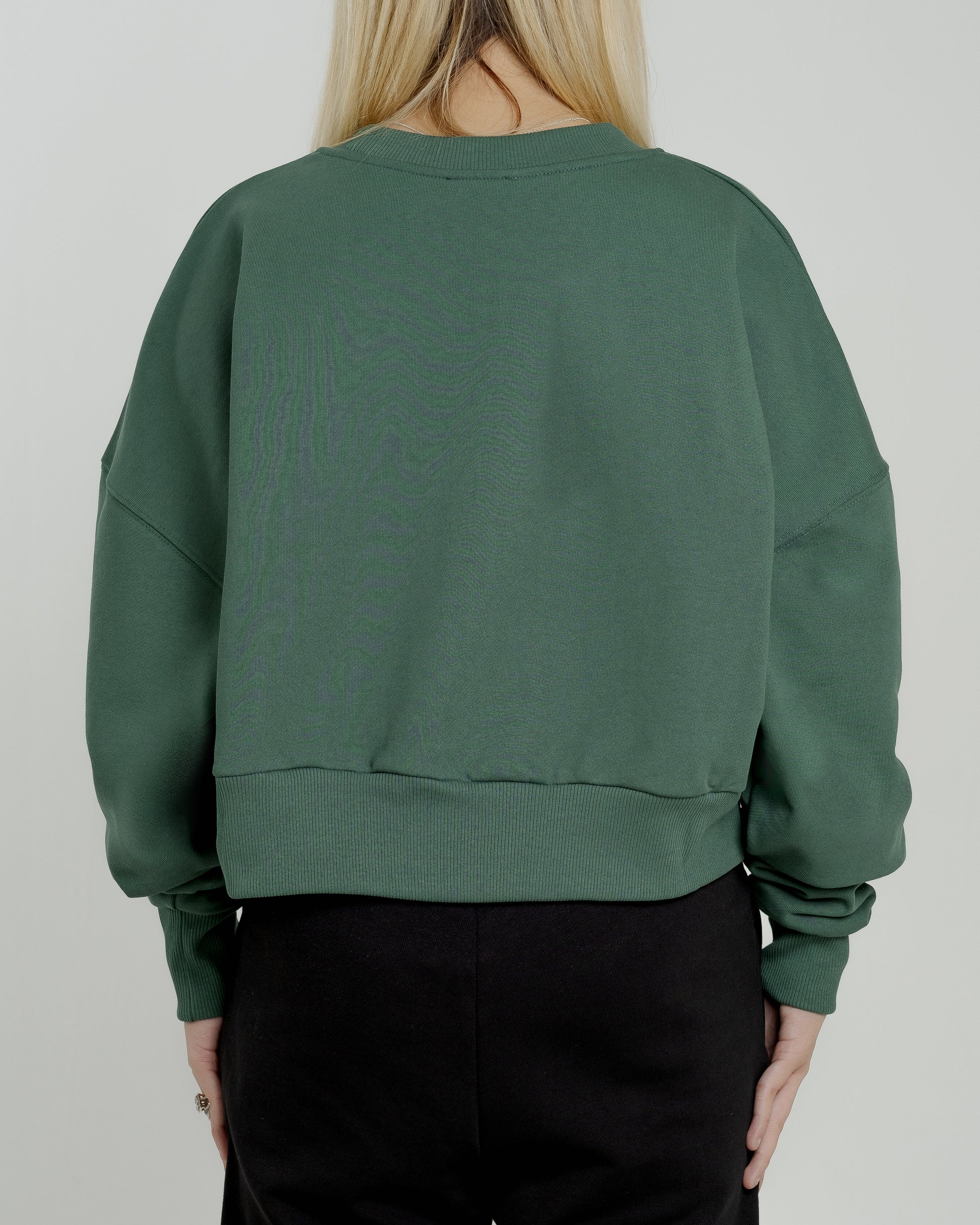 A female model wearing our green women's cropped sweatshirt, exuding a casual and stylish vibe for a modern wardrobe.