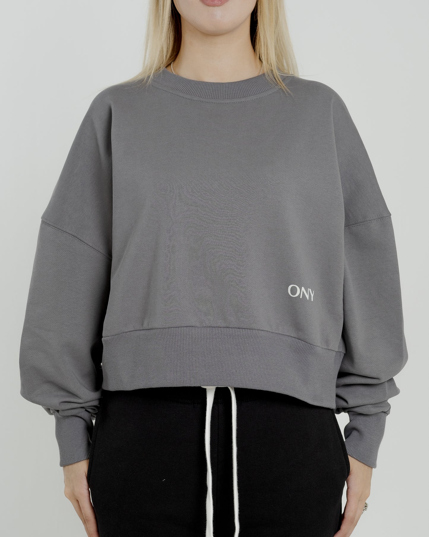 A female model wearing our grey women's cropped sweatshirt, exuding a casual and stylish vibe for a modern wardrobe.