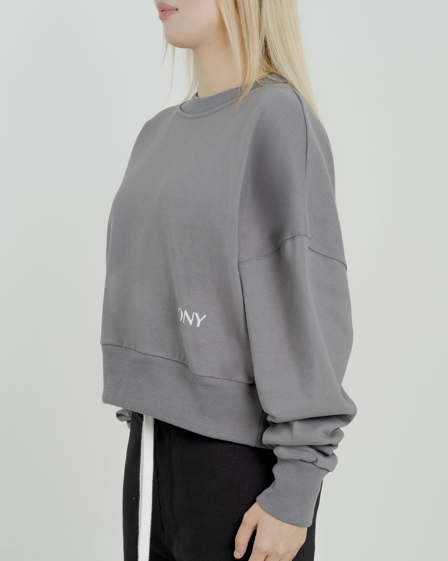 A female model wearing our grey women's cropped sweatshirt, exuding a casual and stylish vibe for a modern wardrobe.