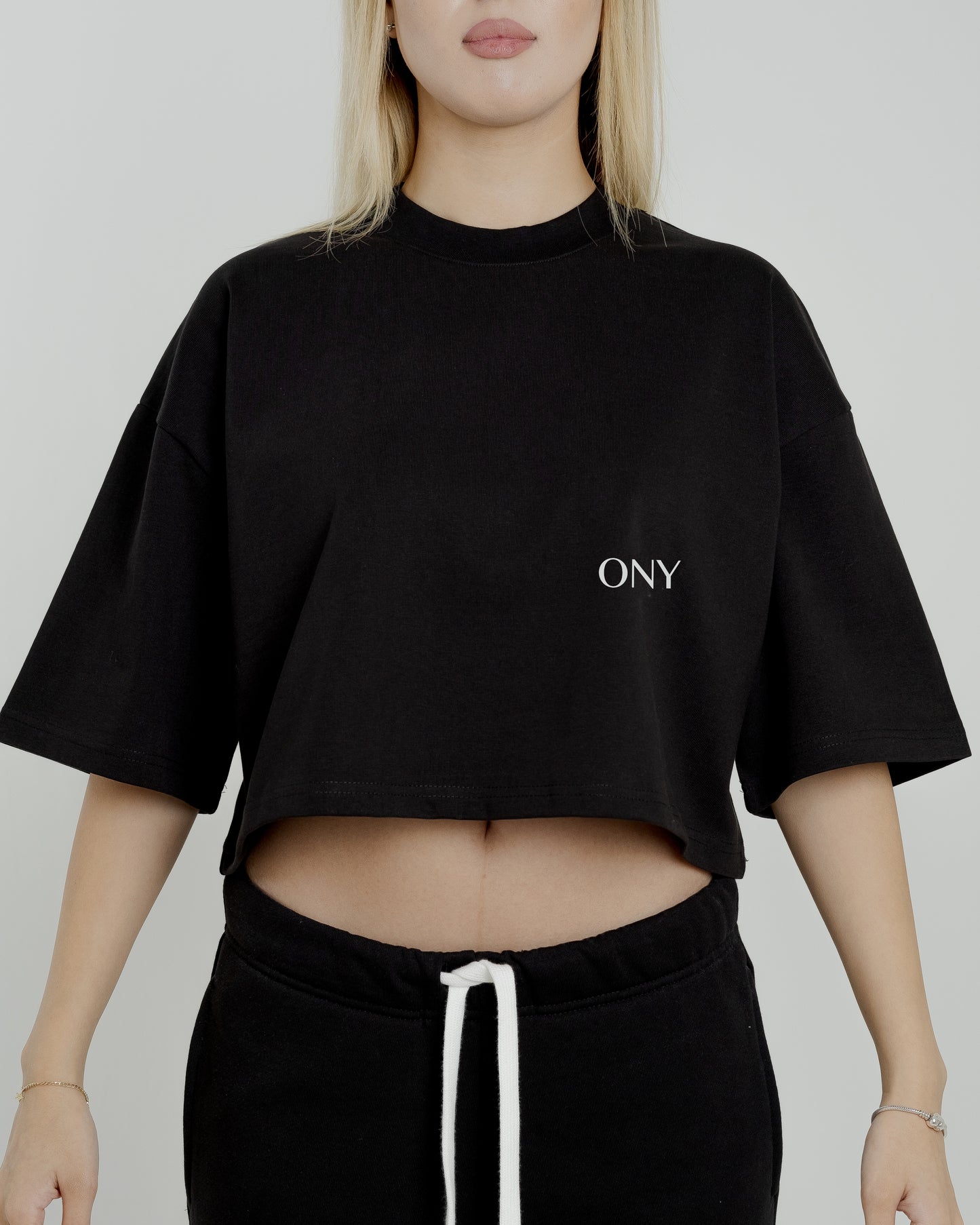 A female model in our black cropped tee, featuring a boxy fit and cropped above the waist for a stylish and relaxed look.