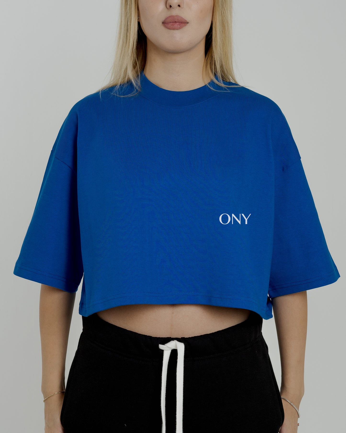 A female model in our blue cropped tee, featuring a boxy fit and cropped above the waist for a stylish and relaxed look.