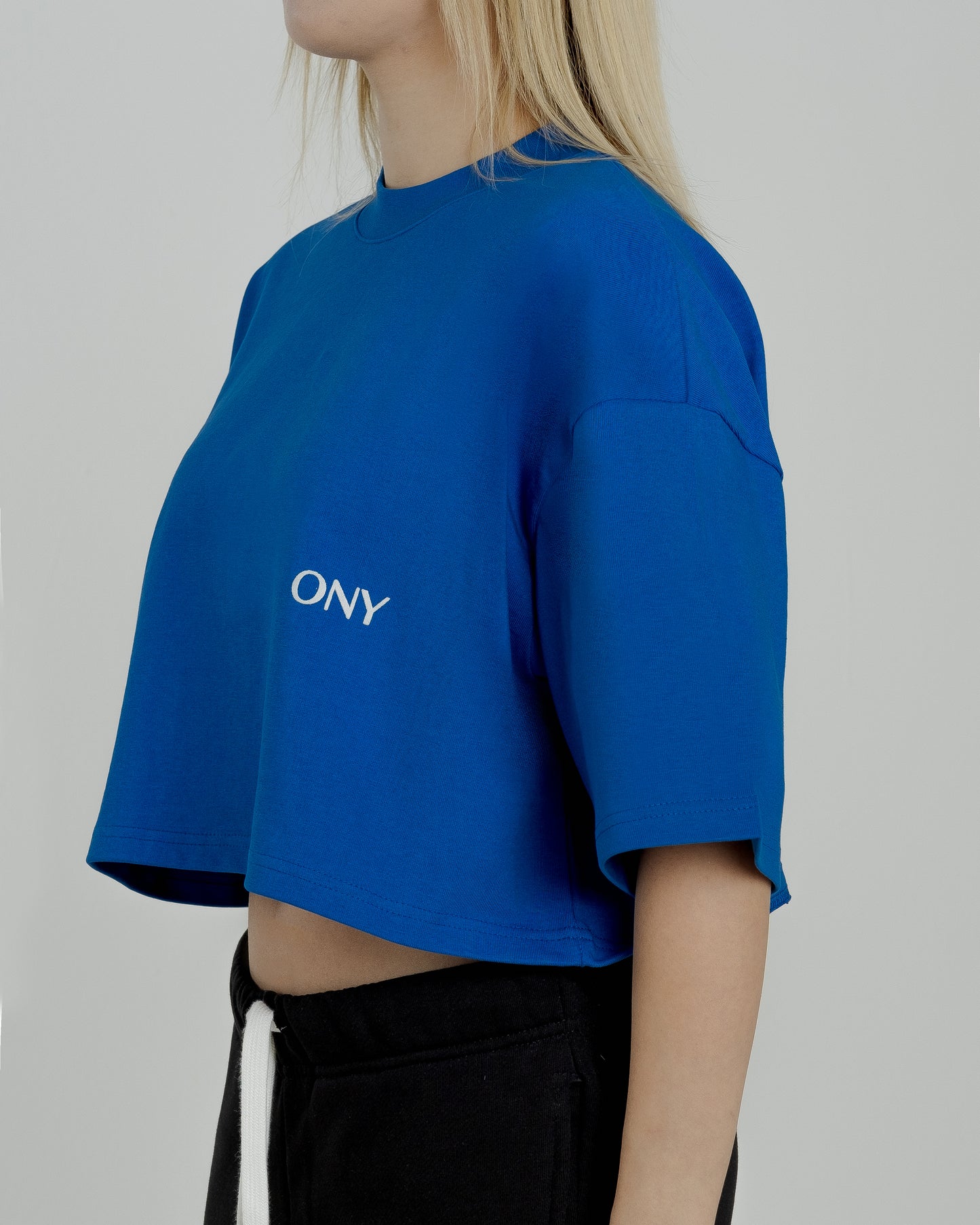 A female model in our blue cropped tee, featuring a boxy fit and cropped above the waist for a stylish and relaxed look.