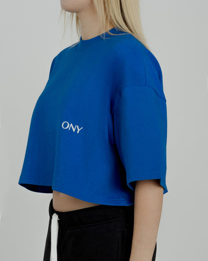 A female model in our blue cropped tee, featuring a boxy fit and cropped above the waist for a stylish and relaxed look.