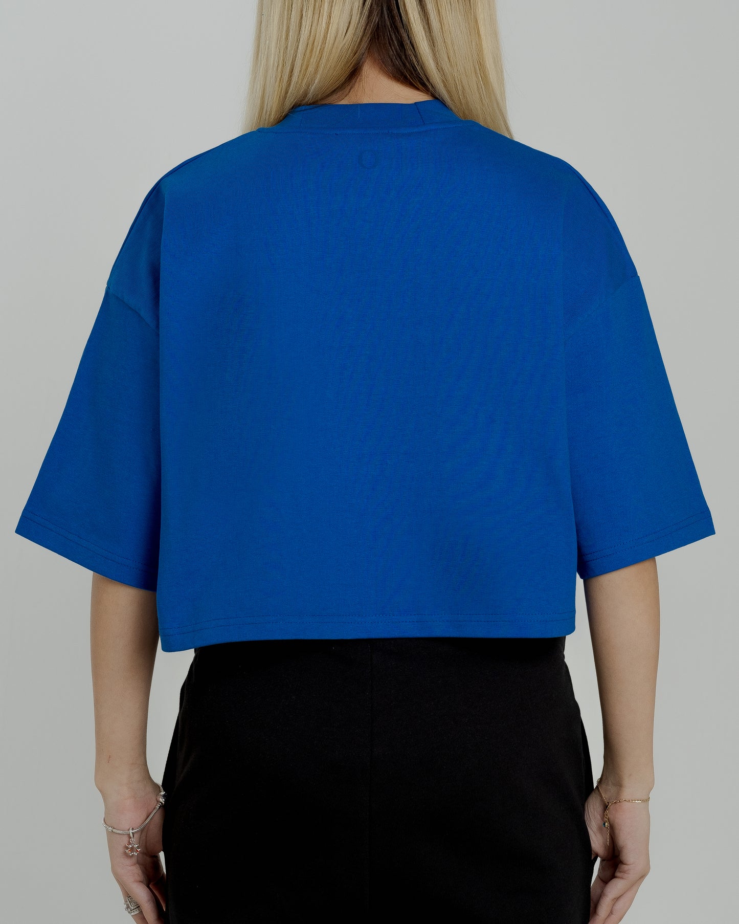 A female model in our blue cropped tee, featuring a boxy fit and cropped above the waist for a stylish and relaxed look.