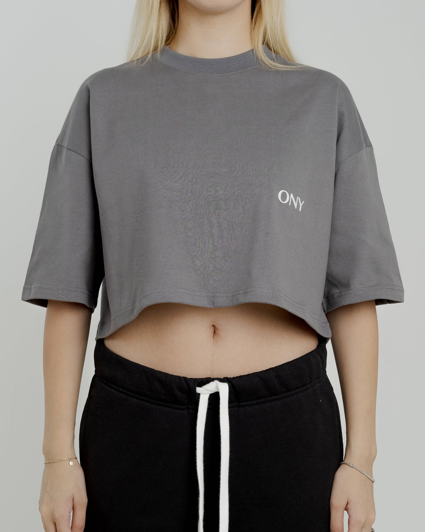 A female model in our grey cropped tee, featuring a boxy fit and cropped above the waist for a stylish and relaxed look.