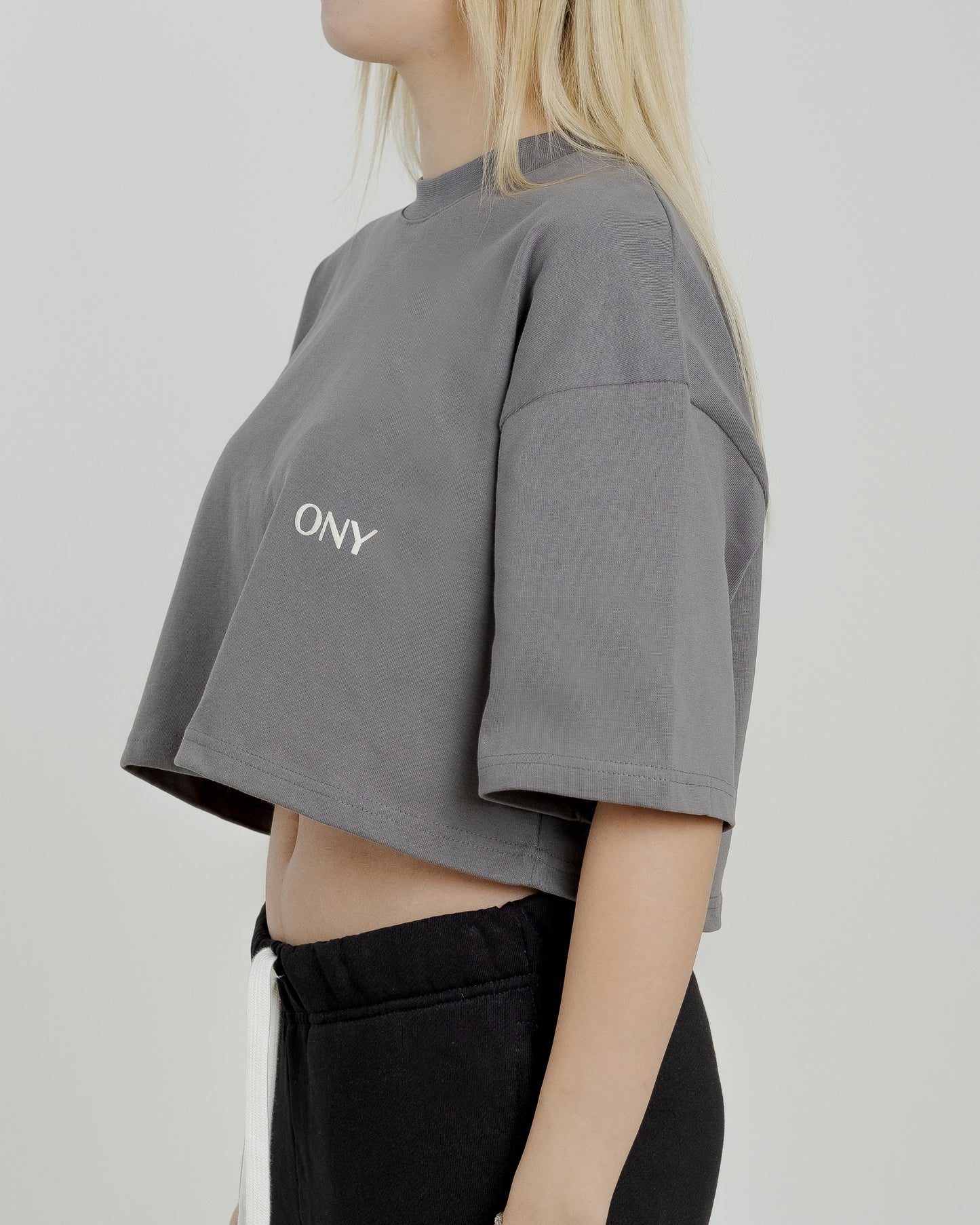 A female model in our grey cropped tee, featuring a boxy fit and cropped above the waist for a stylish and relaxed look.